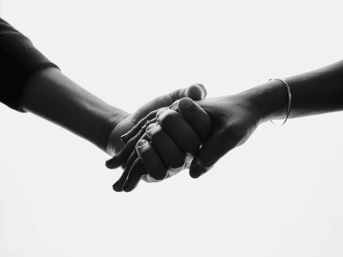 Black and white close-up of two hands clasped together against a white background.